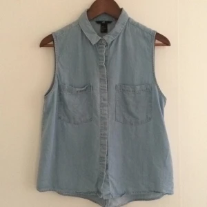  - Söt ärmlös skjorta i denim. Pärlemorknappar! Sparsamt använd.

Hämtas i centrala Göteborg eller skickas mot att köparen betalar frakten.

Köp flera plagg så får du det/de billigare till halva priset.