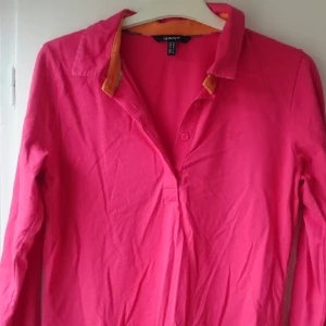  - Hallonrosa jersey med orange innerkrage och rutigt mönster under. Bra skick, använd några få gånger. 100% bomull. Lite stretchig men något hårdare tyg än den militärgröna jag har lagt upp också. Passar den som har 36-40 i strl. Nypris: 899kr 