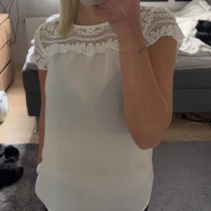 Vit och svart blus från Soyaconcept - Säljer två fina blusar från Soyaconcept. Den ena är vit och den andra är svart, båda med vackra spetsdetaljer vid halsen och ärmarna. Perfekta för både vardag och fest! De har en normal passform och korta ärmar.