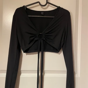 Svart topp - Fin svart topp med en ring i mitten och knytning, använd en gång!