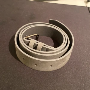 Grått mockabälte - Snyggt grått bälte i mocka som är 110cm långt. Den är oanvänd, jag säljer den eftersom fick den i julklapp men jag har redan en likadan.