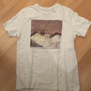 Vit t-shirt med konsttryck från Pull&Bear - Säljer en vit t-shirt från Pull&Bear med ett tryck av Michelangelos 'Skapelsen av Adam'. Säljer den då den har blivit för liten för mig. va inte rädd för att ställa frågor 🌟🌟🌟