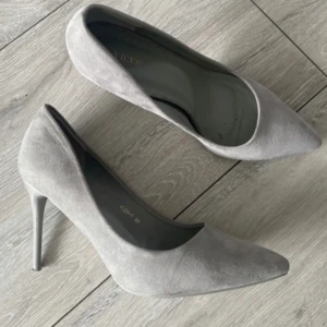 Grå pumps med spetsig tå - Eleganta grå pumps med spetsig tå och hög klack. Perfekta för en stilren look.
