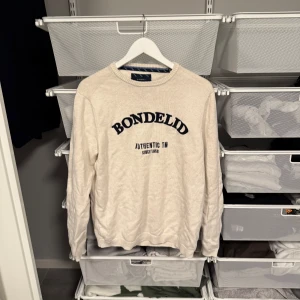 Beige tröja från Bondelid - Säljer en beige tröja från Bondelid med text på framsidan. Tröjan har långa ärmar och en rund halsringning. Storlek L