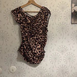 Leopardmönstrad topp - Snygg leopardmönstrad topp med korta ärmar och rund hals. Perfekt för en trendig look. Materialet är mjukt och bekvämt.
