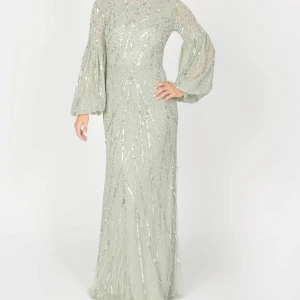 Lång festklänning - Elegant långklänning i ljusgrön med glittrigt mönster. Klänningen har långa, vida ärmar och en figursydd passform som ger en sofistikerad look. Perfekt för speciella tillfällen. Använd endast en gång