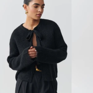 Svart stickad kofta med knytning i fram - Snygg svart stickad kofta med knyt framtill. Ifrån ginatricot och aldrig använd! Säljer då jag inte tycker den sitter fint på mig! Storlek M. 