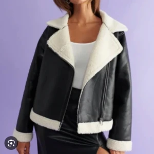 Svart skinnjacka med foder - Säljer en snygg svart skinnjacka från Ginatricot med mysigt vitt teddyfoder. Jackan har en dragkedja och är perfekt för höst och vinter. Den har långa ärmar och en klassisk krage. Perfekt för att hålla sig varm och stilren! 🖤Använd fåtal gånger, säljer därav att den inte kommer till användning🖤Köpt för 800kr, säljer för 300kr