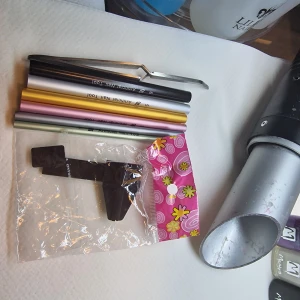 nagelverktyg pinching set - Ett set med färgglada nagelverktyg i olika metalliska färger, inklusive en pincett. Verktygen är designade för nagelvård och kommer i en praktisk förpackning med blommönster.