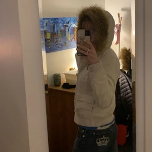 Vit jacka med fuskpäls - Snygg vit jacka med fuskpälsfodrad huva och ribbade muddar. Jackan har dragkedja och knappar framtill samt praktiska fickor med lock. Perfekt för kyliga dagar. Storlek M men passar S🩷🩷