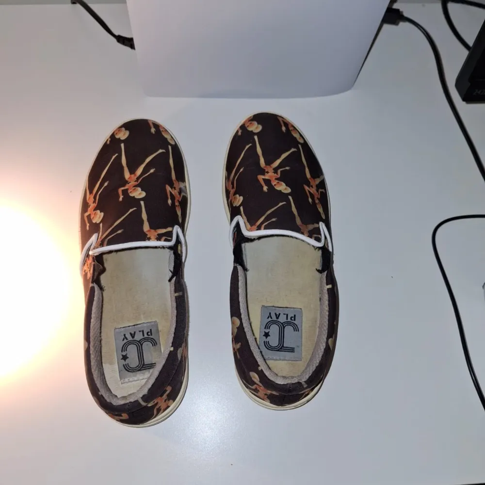 Snygga bruna loafers från JC Play med ett unikt dansmönster i orange och beige. Skorna har en bekväm passform och är perfekta för en avslappnad stil.. Kengät.