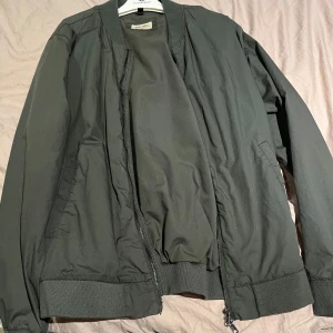 Grön tunn jacka - Snygg grön tunn jacka med dragkedja framtill och ribbade muddar. Perfekt för en stilren look.