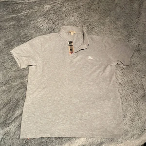 Grå pikétröja från Burberry - Snygg grå pikétröja från Burberry i bra skick.