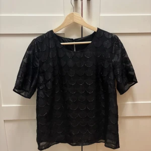 Svart glittrig topp - Snygg svart topp med ett jättefint mönster! Knappt använt den så riktigt bra skick!