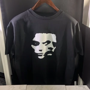 Two-face tshirt  - Snygg svart t-shirt med ett iögonfallande vitt ansiktsmotiv på framsidan. Perfekt för en cool och avslappnad stil. Kortärmad och tillverkad i ett bekvämt material, bra att veta att den sitter lite oversize. Hör av er vid minsta fundering🙌