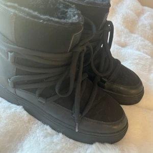 Lik inuikii  - Säljer ett par svarta vinterboots med snörning och varmt foder. Perfekta för kalla dagar med en stilren design och robust sula.