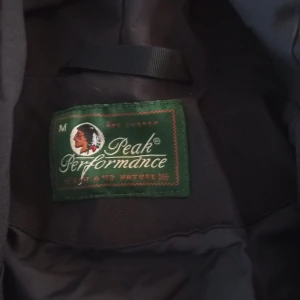 Svart jacka från Peak Performance - Säljer en svart jacka från Peak Performance med huva och dragkedja. Jackan har en sportig look och är perfekt för kyligare dagar.