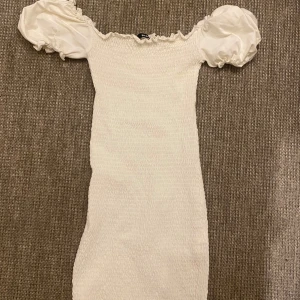 Vit offshoulder klänning med puffärmar - vit klänning med offshoulder-design och puffiga kortärmar, tight passform.  Köpt från bikbok. 