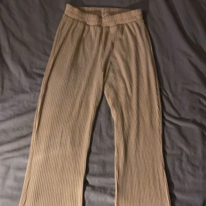 Beige ribbade byxor - Snygga beige ribbade byxor med hög midja och wide fit. Perfekta för en stilren look. Passar bra till både vardag och festliga tillfällen.