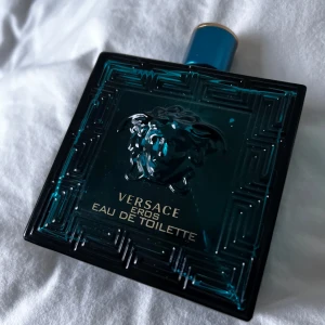 Versace Eros Eau de Toilette - Säljer en flaska Versace Eros Eau de Toilette. Flaskan är i en djup turkos färg med ett elegant mönster och Versaces ikoniska Medusa-logga. Den rymmer 200 ml av denna fräscha och maskulina doft.