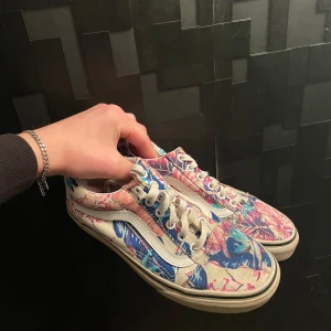 Vans  - Säljer ett par unika Vans sneakers med ett färgglatt mönster i blått, rosa och vitt. Skorna har den klassiska våfflade sulan och snörning framtill. Perfekta för att sätta färg på din outfit.