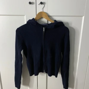 Mörkblå hoodie från Brandy Melville - Säljer en snygg mörkblå hoodie från Brandy Melville. Den är ribbad med dragkedja och har en mysig huva. Perfekt för en avslappnad stil.