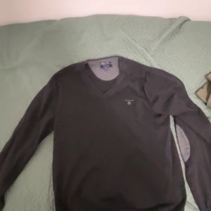 Svart tröja från GANT - Säljer en stilren svart tröja från GANT i storlek M. Tröjan har en v-ringad hals och är tillverkad i bomull. Perfekt för en klassisk och avslappnad look.