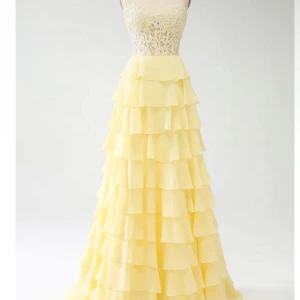 Ljusgul klänning - Säljer den här ljusgula klänningen med en vacker spetsöverdel och volangdetaljer. Klänningen är axelbandslös och har snören som man kan justera i ryggen. Säljer den då den aldrig är använd💗