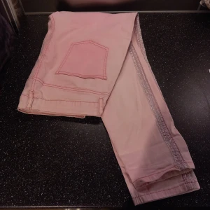 Rosa jeans med glittriga detaljer - Rosa jeans med glittriga detaljer längs sidorna. Inga hål eller andra täcken på att dem använts. 