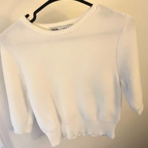 Vit stickad kortärmad tröja från Zara - Säljer en stilren vit tröja från Zara med trekvartsärm. Perfekt för en avslappnad look. Tröjan har en rund halsringning och ribbade kanter som ger en snygg finish.