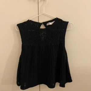 Svart spetslinne från Zara - Säljer ett svart spetslinne från Zara. Det är ärmlöst och har en elegant spetsdesign som ger en stilren look. Perfekt för att klä upp en outfit eller bära som det är för en mer avslappnad stil.