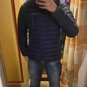 Säljer en stilren svart dunjacka från Peak Performance. Jackan har en praktisk dragkedja och är långärmad med en bekväm passform. Perfekt för kyligare dagar med sin quiltade design.