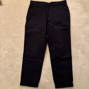 Svarta chinos - Snygga svarta chinos med normal passform. De har en klassisk design med knappar och dragkedja framtill. Perfekta för en stilren look. Storlek 32/32. Mycket bra skick.