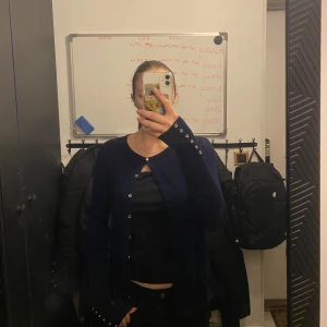 Mörkblå kofta med knappar - Säljer en stilren mörkblå kofta med knappar framtill. Perfekt för lager-på-lager och passar till många olika outfits. Koftan har långa ärmar och en klassisk design.