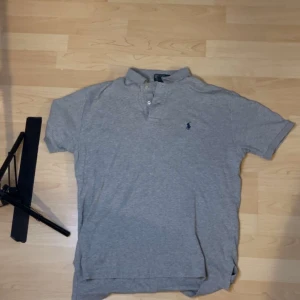 Grå pikétröja från Polo Ralph Lauren - Säljer en klassisk grå pikétröja från Polo Ralph Lauren med korta ärmar.