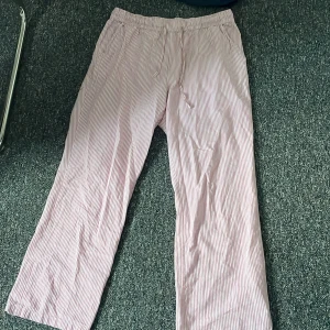 Randiga byxor i bomull - Säljer ett par bekväma randiga pyjamasbyxor i bomull. De har en avslappnad passform med elastisk midja för extra komfort. Perfekta för en avslappnad dag hemma.