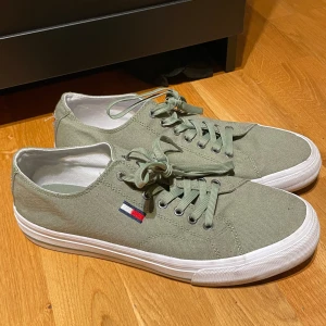 Gröna sneakers från Tommy Hilfiger - Snygga gröna sneakers från Tommy Hilfiger med klassisk snörning och vit sula. Perfekta för en avslappnad stil. Strl 44.