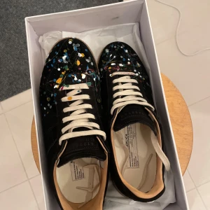 Svarta sneakers med färgglatt mönster - Snygga svarta sneakers med unikt färgglatt mönster och vita snören har inget fast pris som kom gärna med förslag då jag inte riktigt vet värdet