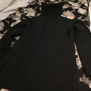 Svart ribbad polotröja från Bik Bok kan snacka om pris  - Säljer en stilren svart ribbad polotröja från Bik Bok. Perfekt för kyliga dagar med sin höga krage och långa ärmar. Tröjan är både bekväm och trendig, idealisk för lager-på-lager-stil.