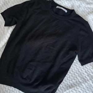 Svart tröja från Zara - Säljer en stilren svart tröja från Zara. Tröjan har korta ärmar och en rund halsringning. Aldrig använd endast testad! 