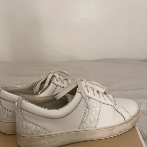 Vita sneakers från Michael Kors - Snygga vita sneakers från Michael Kors med diskret logotypmönster på sidan. Köpt för 1200kr men har använt de mycket så de är lite slitna vid inerhälen. Pris kan diskuteras 🩷