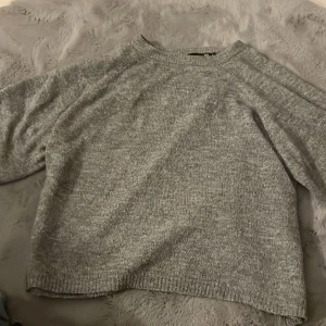 Grå stickad tröja från 157 - Mysig grå stickad tröja från lager 157. Perfekt för vårdagar med sin bekväma passform och korta ärmar. Ett måste i garderoben för en stilren look.