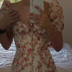 House of CB  - Världens finaste klänning från House of CB som kommer med original förpackning! Den är vit med rosa ros detaljer. Helt ny och använd endast en gång! I storlek XS (32-34) men är justerbar eftersom den är korsett lik! 