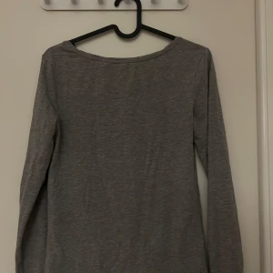 Grå långärmad tröja från 157 - Säljer en enkel och stilren grå långärmad tröja från 157. Perfekt för vardagsbruk och kan lätt matchas med olika outfits. Tröjan är i bra skick och gjord av mjukt material för extra komfort. Passar perfekt för höst och vår!