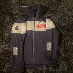 Seglarjacka från Helly Hansen i toppskick! Nypris runt 3800kr. Storlek S passar runt 180 och luvan går att stoppa in i kragen ifall man vill det. Herrmodell men passar både tjej & kille!