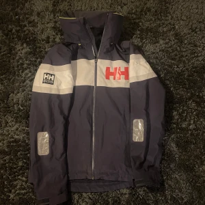 Helly Hansen Seglarjacka - Seglarjacka från Helly Hansen i toppskick! Nypris runt 3800kr. Storlek S passar runt 180 och luvan går att stoppa in i kragen ifall man vill det. Herrmodell men passar både tjej & kille!