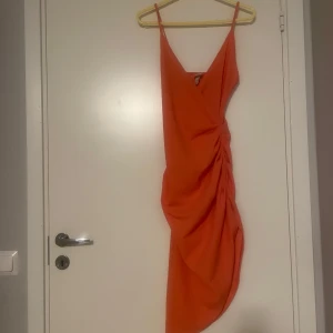 Orange klänning  - Säljer en snygg orange draperad klänning med slits från H&M. Lite nopprig.