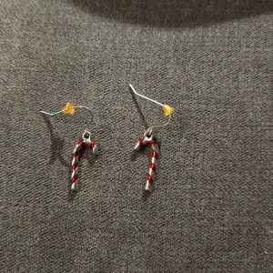 Örhängen med polkagrisdesign - Söta örhängen i form av polkagrisar, perfekta för julens festligheter! De är i silverfärg med röda och vita ränder, vilket ger en klassisk och lekfull look. Passar perfekt för att ge din outfit en extra touch av julstämning. 🎄