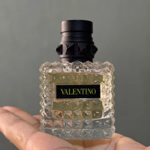 Valentino parfymflaska - Säljer en elegant parfym från Valentino. Flaskan är fyrkantig med ett lyxigt mönster och svart lock. Perfekt för den som vill ha en stilren och exklusiv doft på hyllan. Flaskan rymmer 30 ml Eau de Parfum.