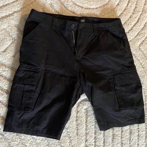 Svarta shorts - Svarta shorts med fickor på benen. Oanvända från Lager 157. 